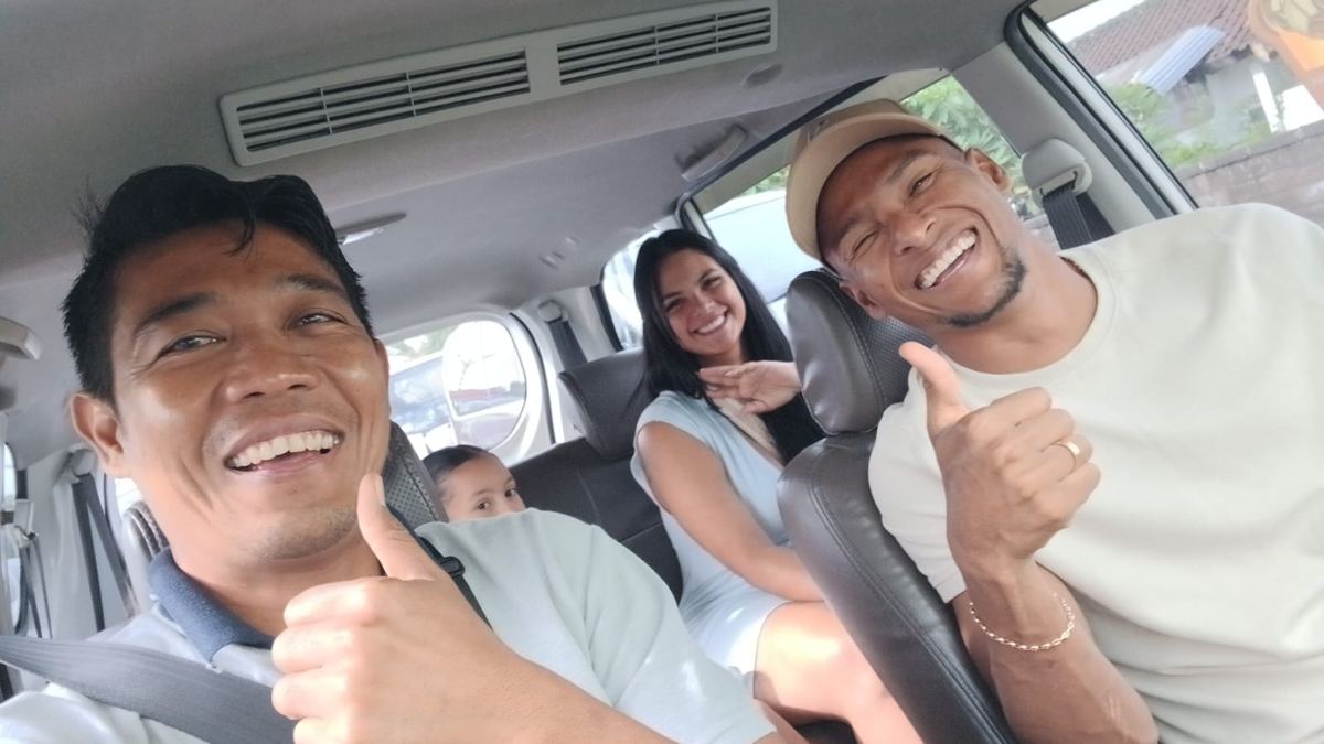 Driver and guests, including a child, smiling in the car